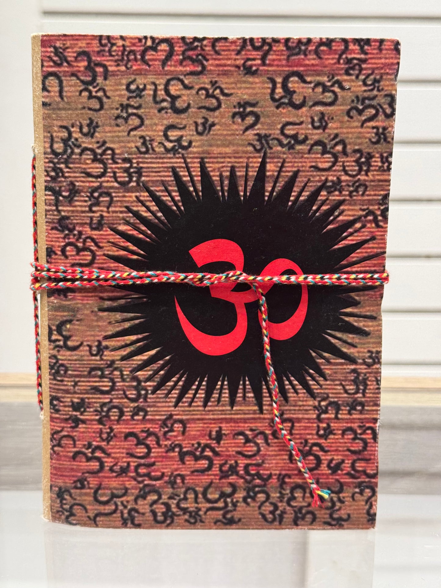 Patterned notebook with a red and black design tied with string.